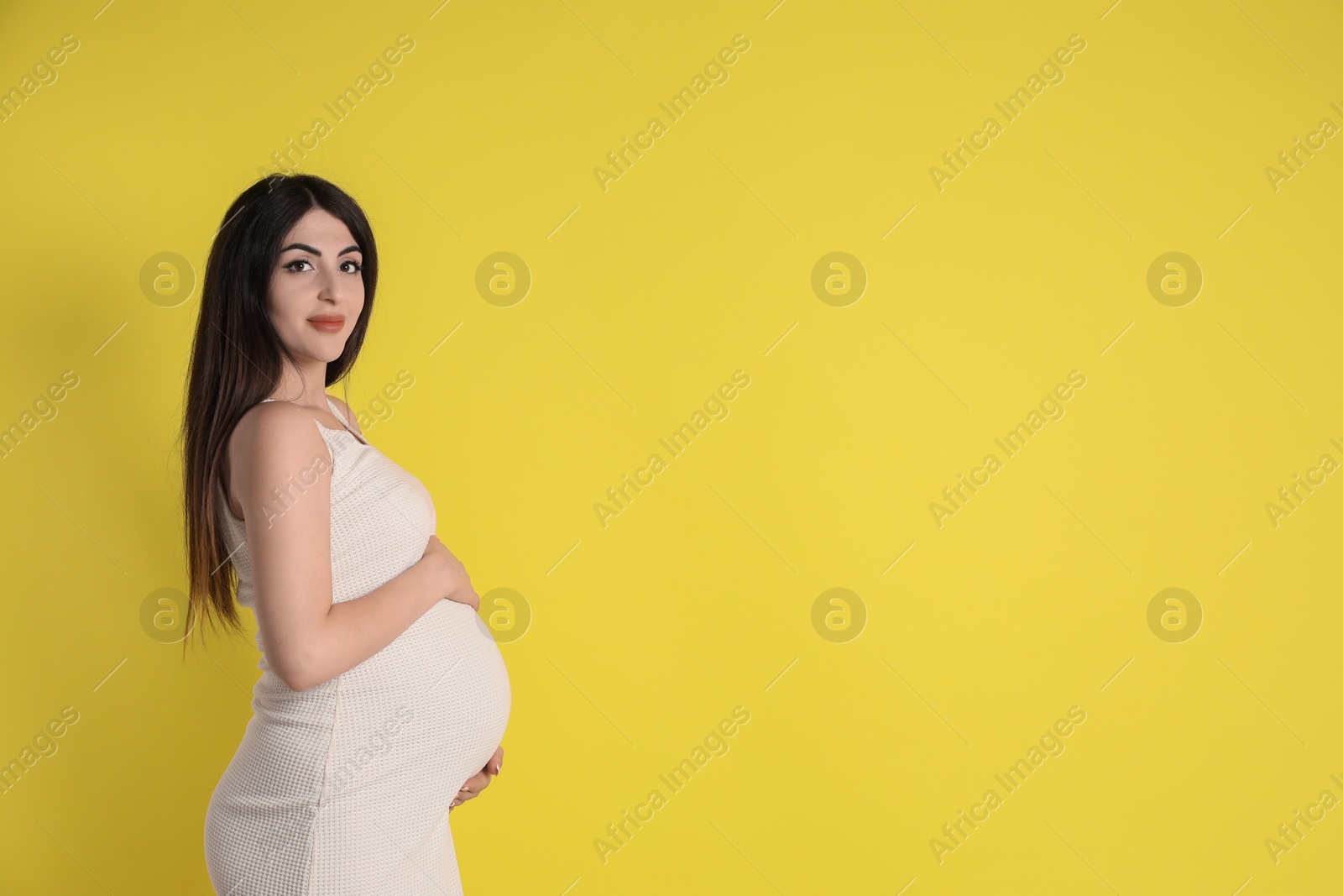 Photo of Portrait of beautiful pregnant woman on yellow background, space for text