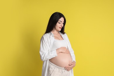 Photo of Portrait of beautiful pregnant woman on yellow background