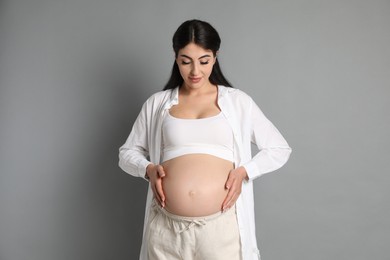 Photo of Portrait of beautiful pregnant woman on grey background