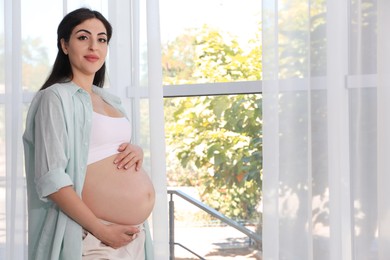 Photo of Portrait of beautiful pregnant woman at home, space for text