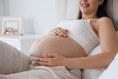 Photo of Young pregnant woman lying on bed at home, closeup