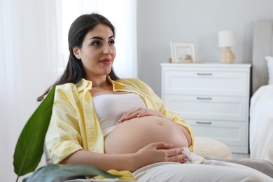 Photo of Young pregnant woman lying on bed at home