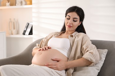 Young pregnant woman lying on bed at home