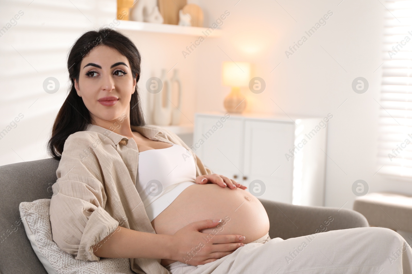 Photo of Young pregnant woman lying on bed at home, space for text