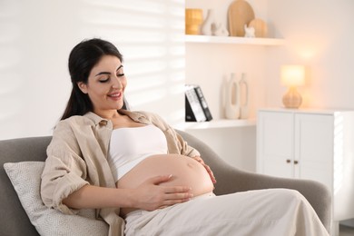 Photo of Young pregnant woman lying on bed at home