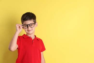 Photo of Portrait of cute little boy on yellow background, space for text