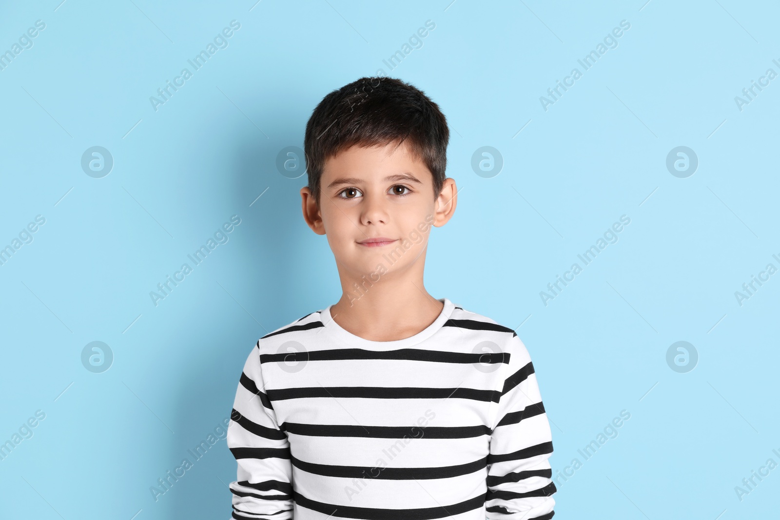 Photo of Portrait of cute little boy on light blue background