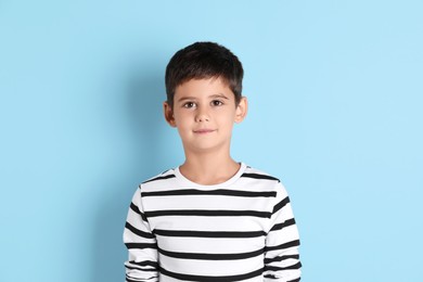 Portrait of cute little boy on light blue background