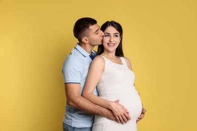 Photo of Beautiful pregnant woman with her husband on yellow background