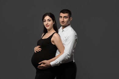 Photo of Beautiful pregnant woman with her husband on grey background