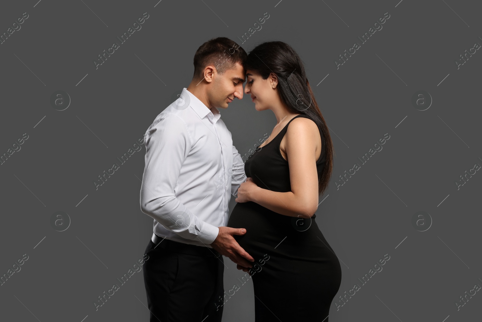 Photo of Beautiful pregnant woman with her husband on grey background