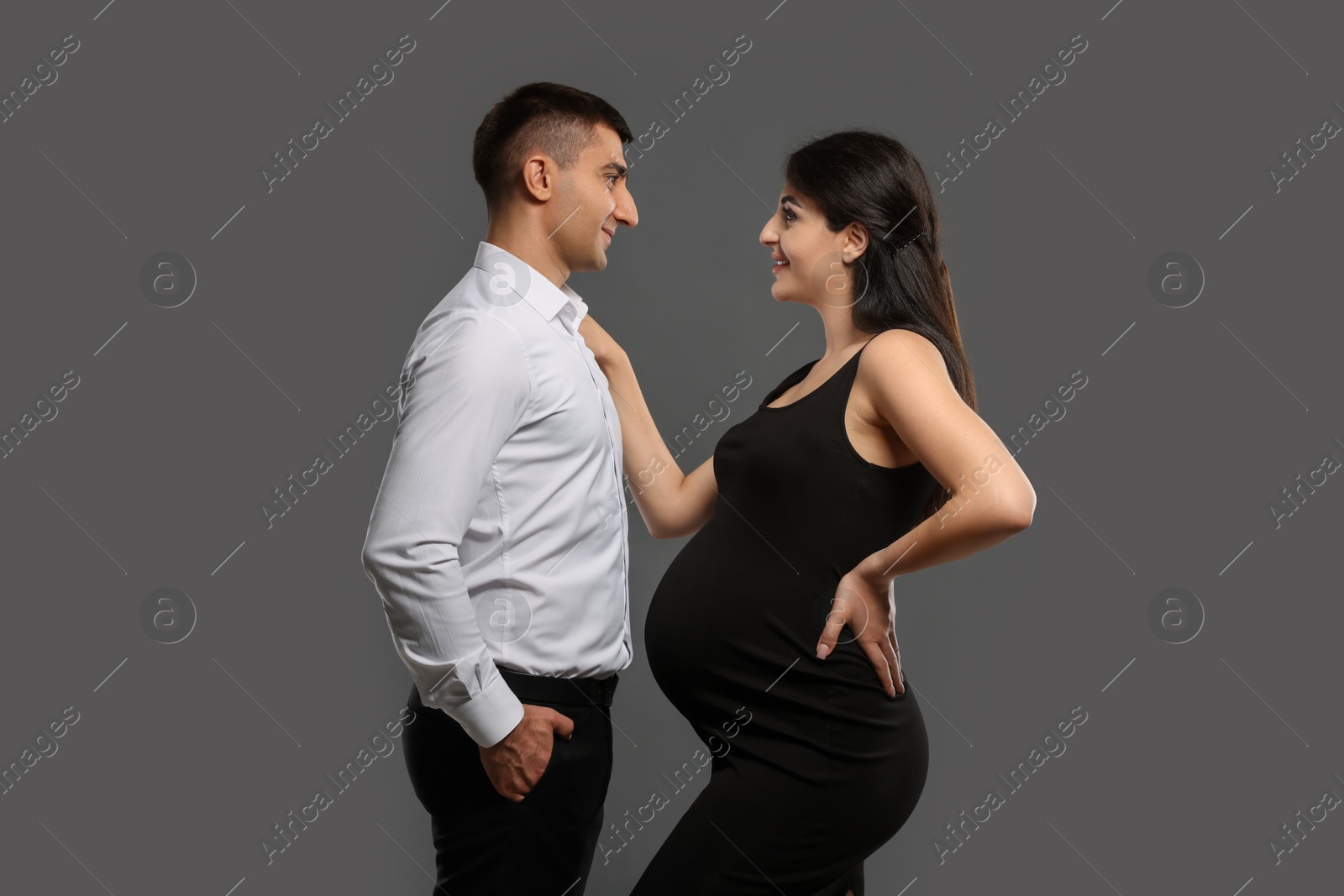 Photo of Beautiful pregnant woman with her husband on grey background