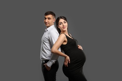 Photo of Beautiful pregnant woman with her husband on grey background