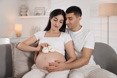 Beautiful pregnant woman with baby booties and her husband at home