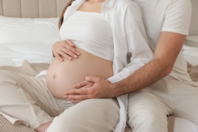 Photo of Man touching his pregnant wife's belly in bedroom, closeup