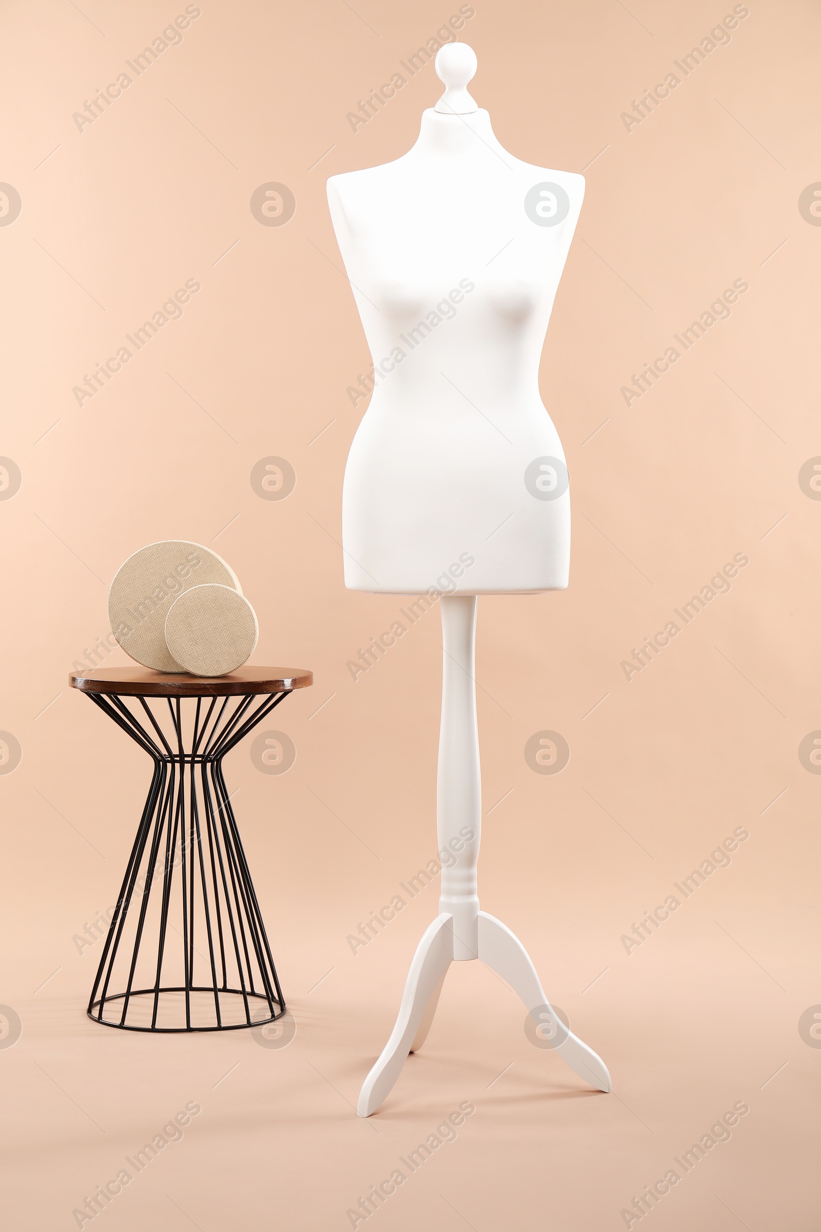 Photo of One female mannequin on stand and coffee table with round boxes against beige background