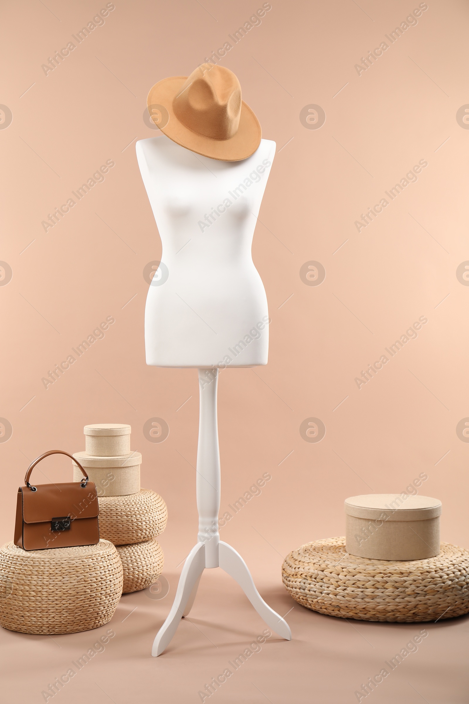 Photo of One female mannequin with hat, poufs, bag and boxes on beige background