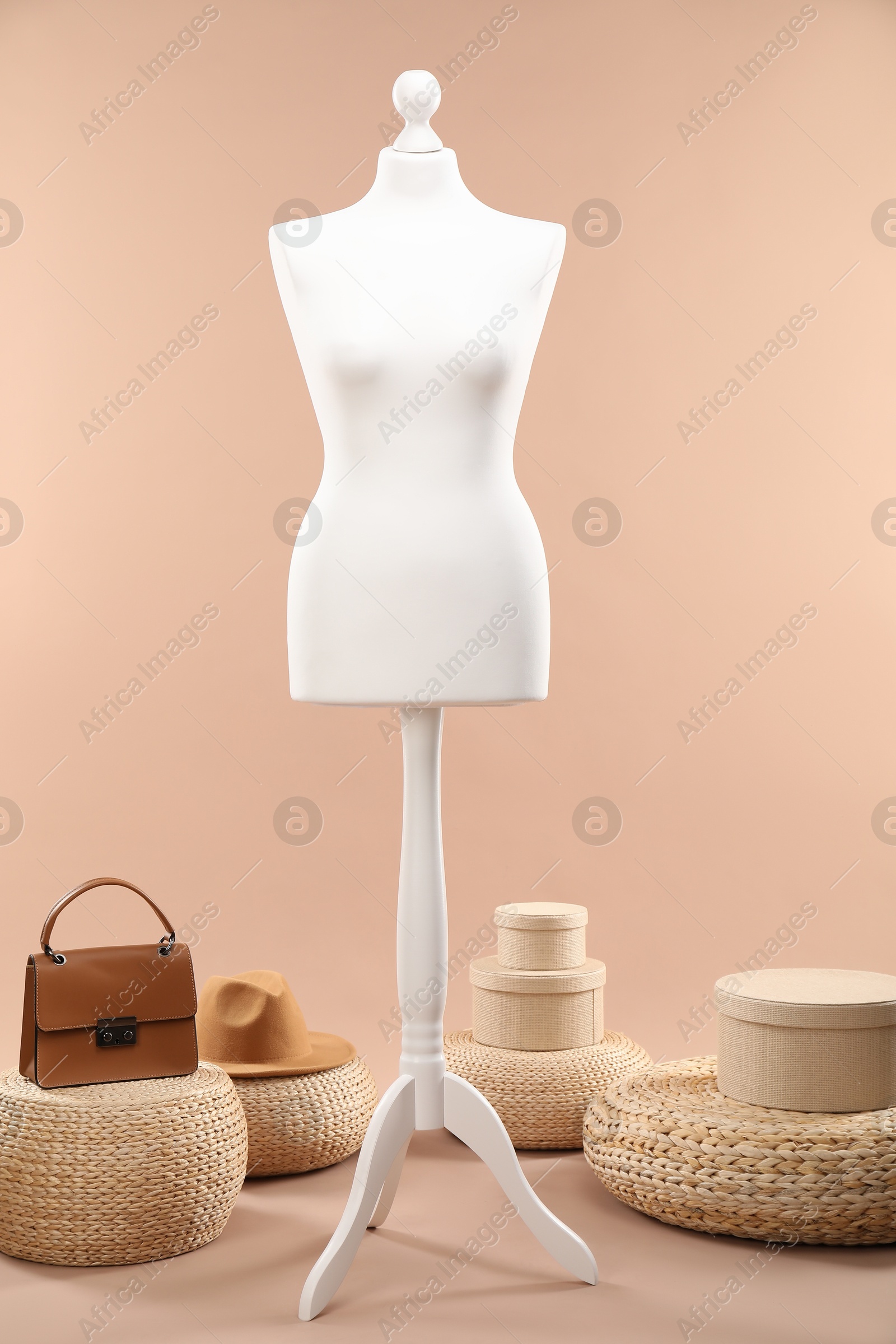 Photo of One female mannequin, poufs, bag, hat and boxes on beige background