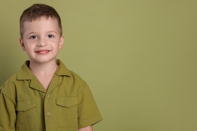 Portrait of cute little boy on green background, space for text