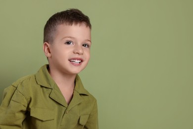 Photo of Portrait of cute little boy on green background, space for text