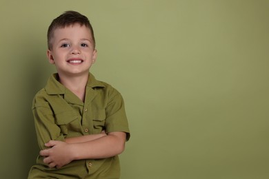 Portrait of cute little boy on green background, space for text