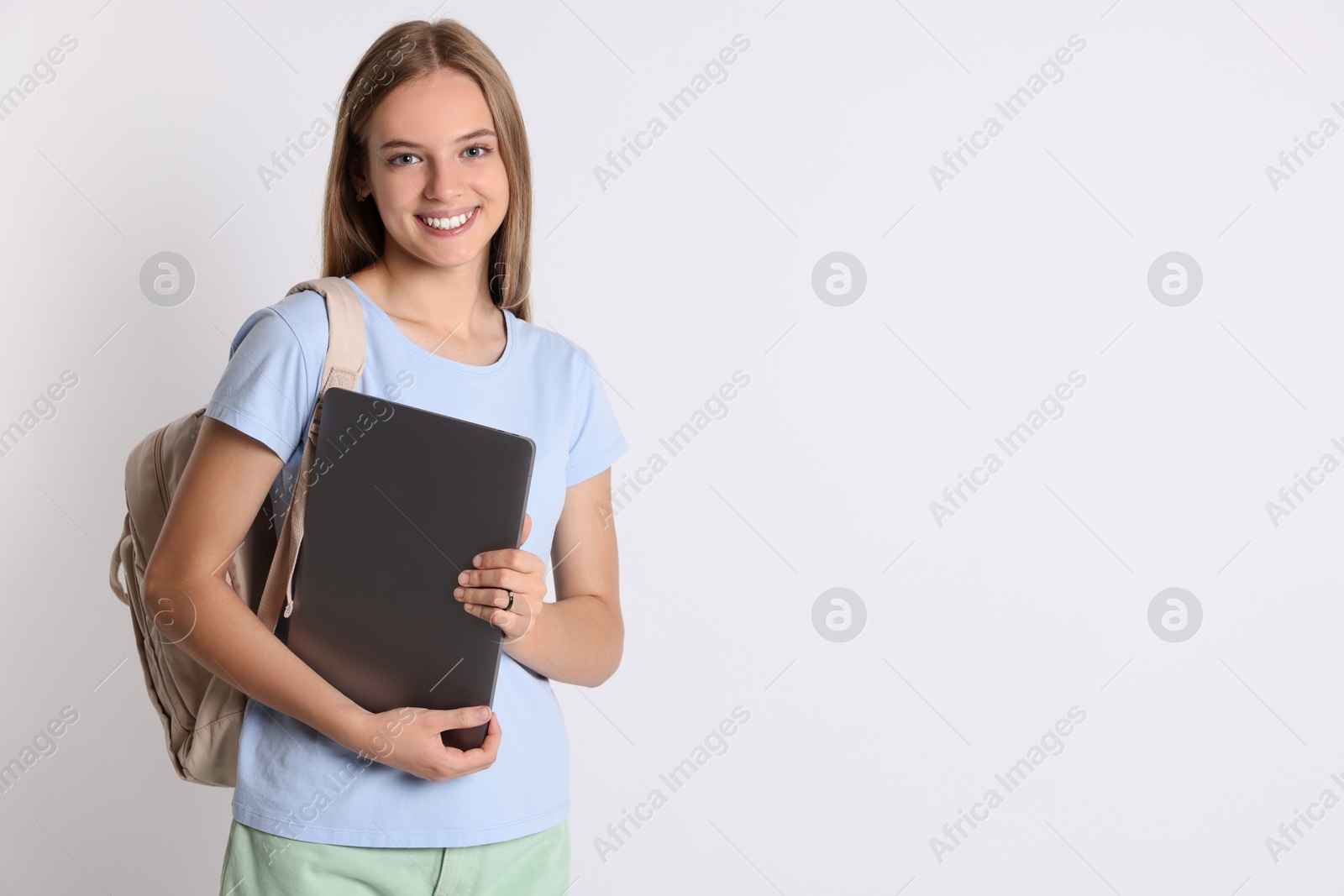 Photo of Teenage girl with laptop and backpack on white background, space for text