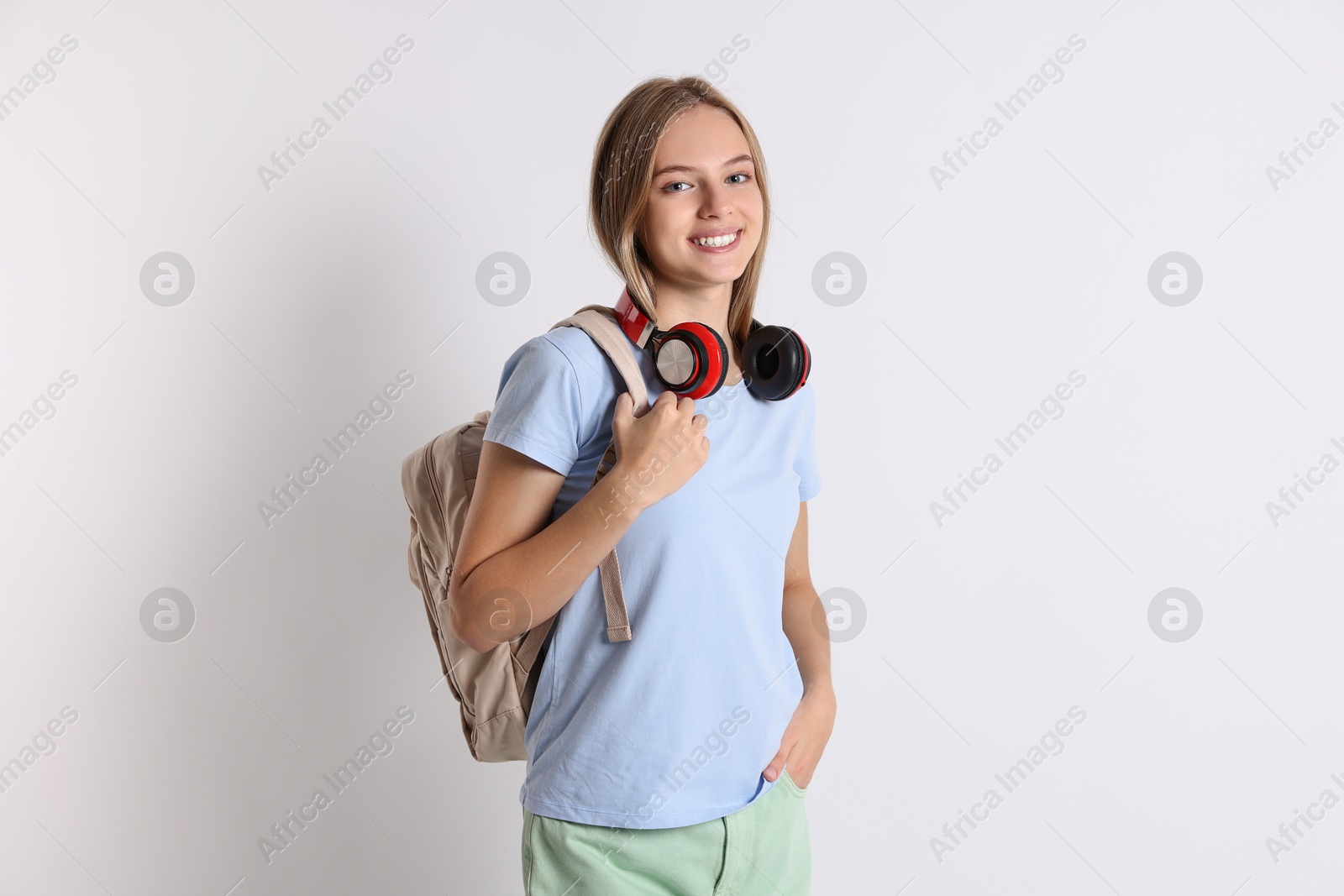 Photo of Teenage girl with headphones and backpack on white background