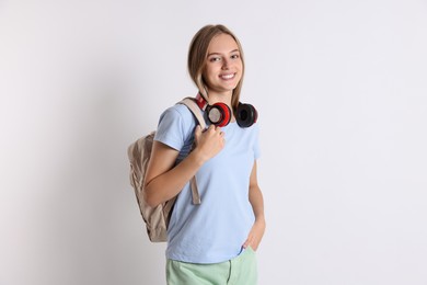 Teenage girl with headphones and backpack on white background