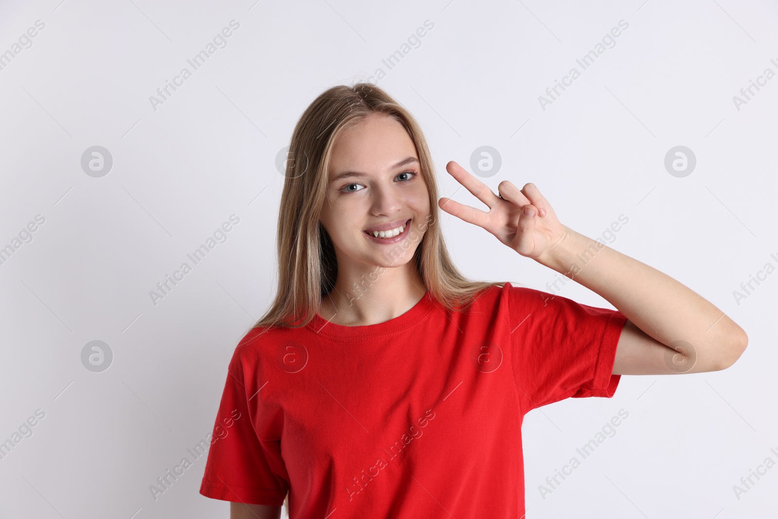 Photo of Teenage girl showing v-sign on white background