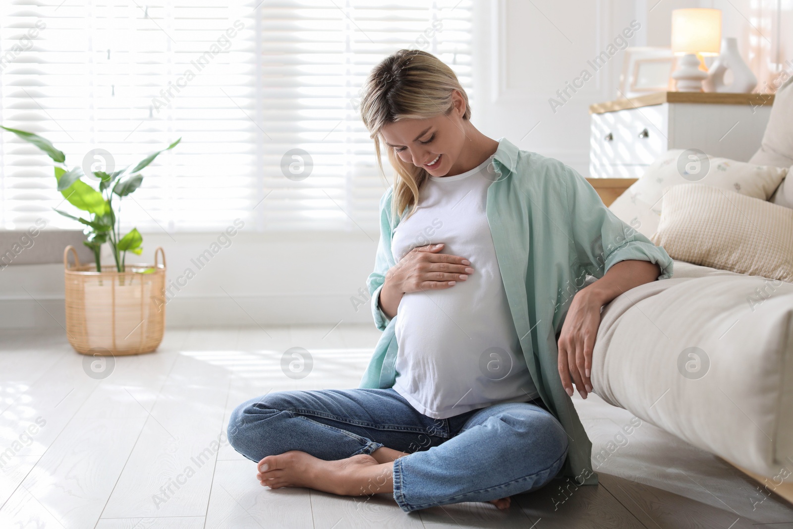 Photo of Portrait of beautiful pregnant woman on floor at home