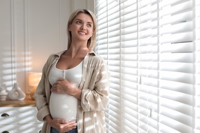 Photo of Portrait of beautiful pregnant woman near window at home