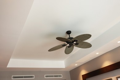 Photo of Modern ceiling fan indoors, low angle view