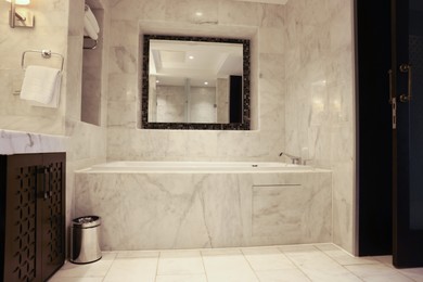 Stylish bathroom with marble bathtub and mirror in luxury hotel