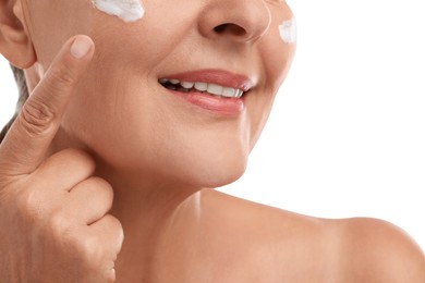 Photo of Senior woman with face cream on white background, closeup