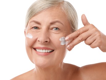 Photo of Senior woman applying face cream on white background