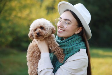 Smiling woman with cute dog in autumn park