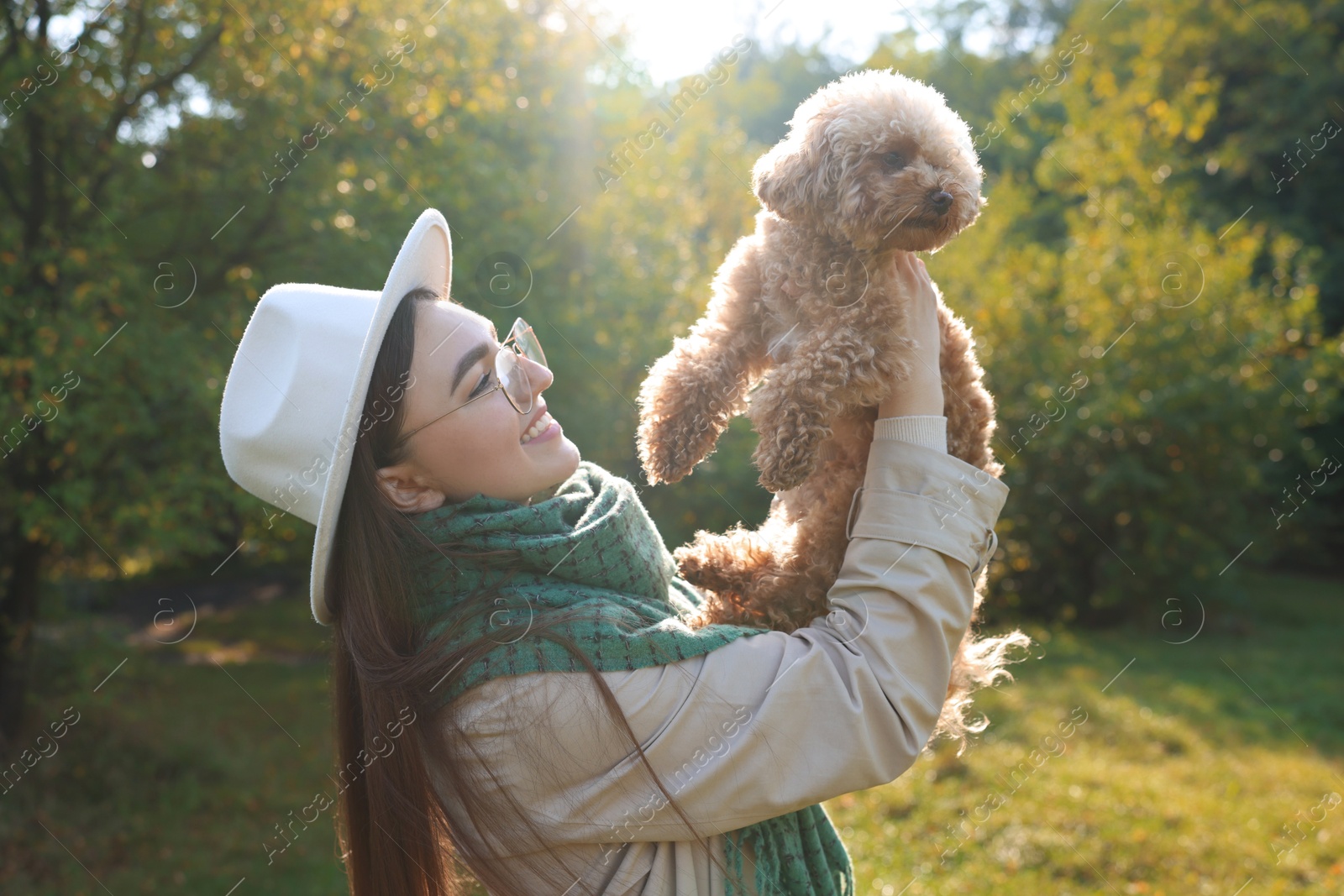 Photo of Smiling woman with cute dog in autumn park on sunny day