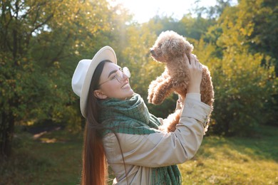 Smiling woman with cute dog in autumn park on sunny day