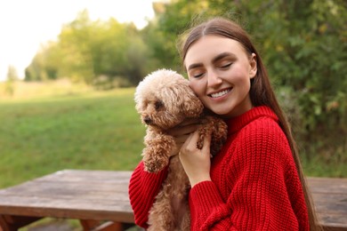 Smiling woman with cute dog in autumn park. Space for text