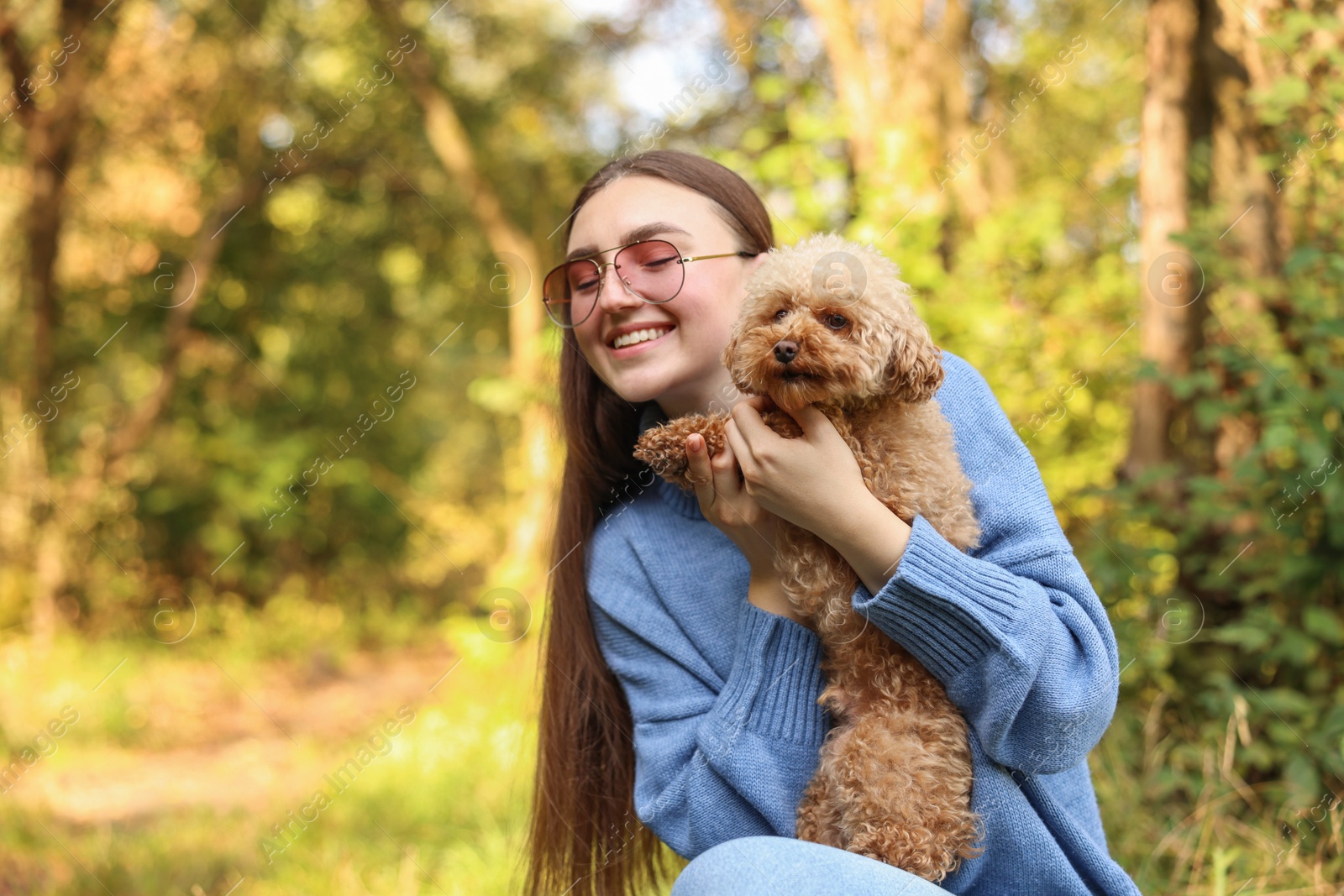 Photo of Smiling woman with cute dog in autumn park. Space for text