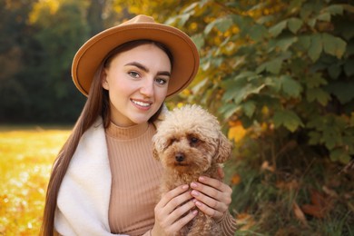 Photo of Smiling woman with cute dog in autumn park. Space for text