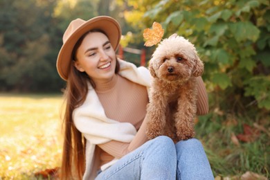 Smiling woman with cute dog in autumn park, selective focus