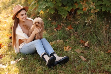 Smiling woman with cute dog in autumn park. Space for text