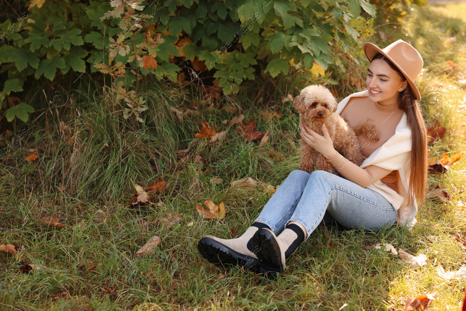 Photo of Smiling woman with cute dog in autumn park. Space for text