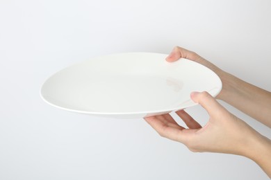 Woman with empty ceramic plate on white background, closeup