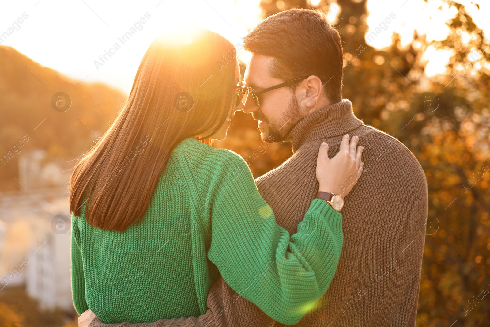 Photo of Cute couple enjoying autumn evening outdoors together, back view