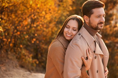 Photo of Beautiful couple hugging in autumn park, space for text