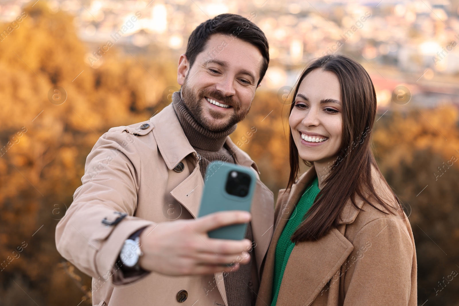 Photo of Beautiful couple taking selfie together outdoors on autumn day