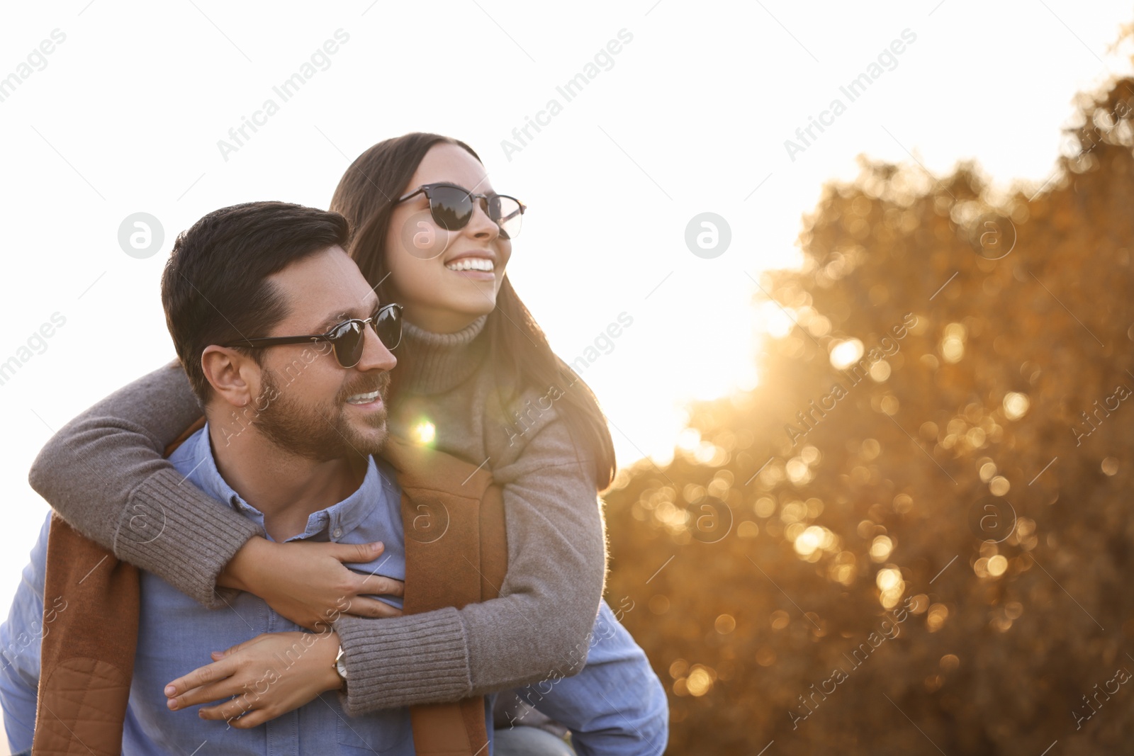 Photo of Beautiful couple having fun together in autumn park, low angle view. Space for text