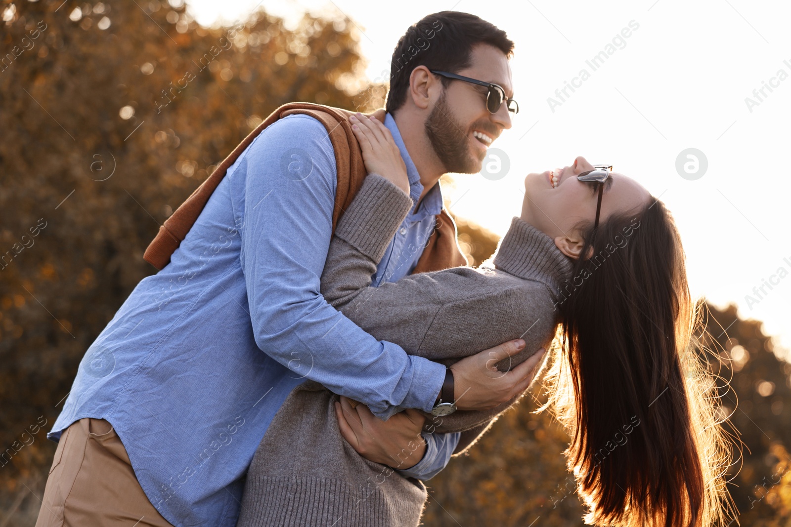 Photo of Beautiful couple having fun together in autumn park, low angle view